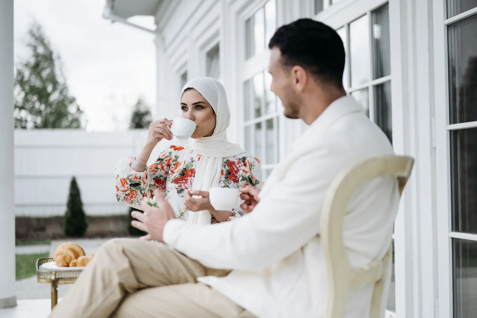 A couple sharing tea and talking on a sunny porch